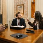 Profissionais discutem em um escritório jurídico diante de um computador.
