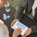 Pessoa preenchendo um formulário de registro eleitoral em um tablet durante atendimento em uma estação de votação