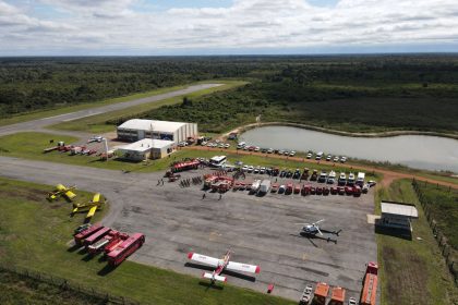 Vista aérea de uma base de combate a incêndios em Mato Grosso, com caminhões, helicópteros e aviões de emergência.