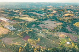 Vista aérea de áreas agrícolas e do campo no Centro do Rio Grande do Sul, durante o dia.